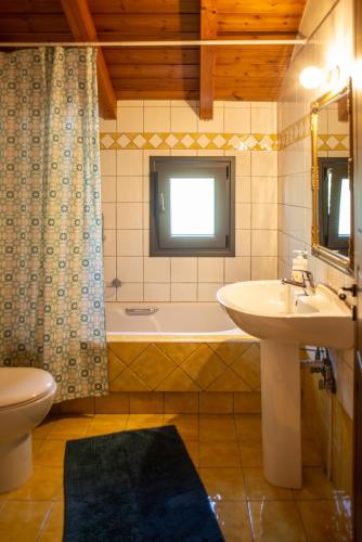 a bathroom with a sink and a tub and a toilet at Agnes Cottage House in Konitsa