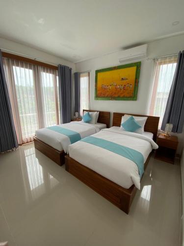 two beds in a room with windows at Villa Dua Warna Dencarik in Lovina