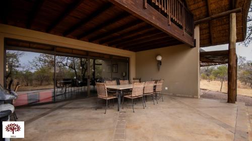 a dining room with a table and chairs on a patio at Zebula Golf and Wildlife Estate - Jackals Call Pax 8 - Moi Signature Luxury villa in Mabula