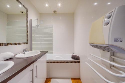 - une salle de bains blanche avec deux lavabos, une baignoire et une chambre dans l'établissement MDOR - Le Montesquieu en bail mobilité, à Bordeaux