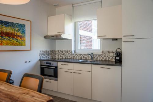 a kitchen with white cabinets and a table and a window at Buitenplaats De Mechelerhof in Mechelen
