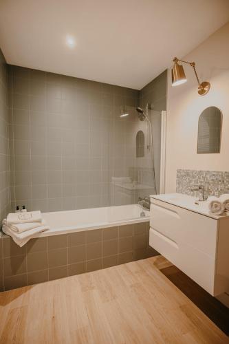une salle de bain avec une baignoire et un lavabo dans l'établissement La maison au bord de l'eau, à Pleudihen-sur-Rance