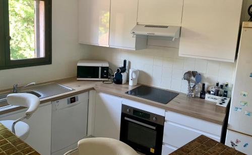 une petite cuisine avec des armoires blanches et un évier dans l'établissement 3P 65 m2 au calme colline de Cagnes sur Mer, à Cagnes-sur-Mer