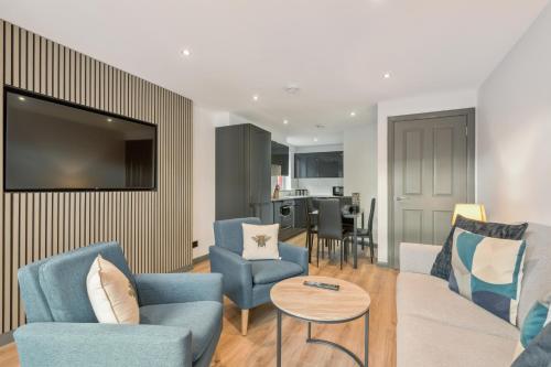 a living room with blue chairs and a tv at Holyrood Aparthotel in Edinburgh