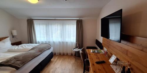 a hotel room with a bed and a flat screen tv at Hotel Restaurant Waldsägmühle in Pfalzgrafenweiler