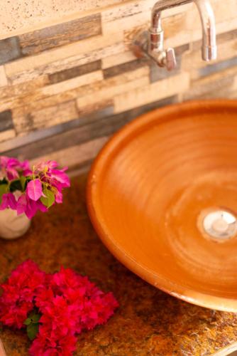 an orange sink with red flowers on a counter at Pousada Nascer da Lua in Fortim