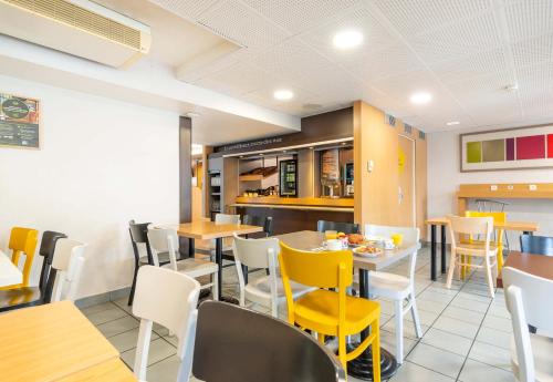 une salle à manger avec des chaises et des tables jaunes dans l'établissement B&B HOTEL Nantes Parc Expos La Chapelle, à La Chapelle-sur-Erdre