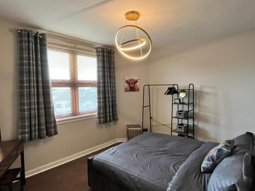 a bedroom with a bed and a chandelier at CENTRAL SERVICED APARTMENTS - 2 Double Bedrooms - Monifieth - Sleeps 4 - Modern & Unique - Smart TV & WiFi - Fully Equipped Kitchen - Spacious & Unique in Monifieth