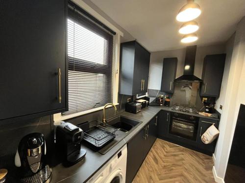 a small kitchen with a sink and a stove at CENTRAL SERVICED APARTMENTS - 2 Double Bedrooms - Monifieth - Sleeps 4 - Modern & Unique - Smart TV & WiFi - Fully Equipped Kitchen - Spacious & Unique in Monifieth