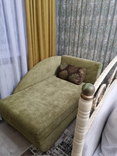 a green couch sitting next to a bed in a room at 2-ка, центр города in Taraz