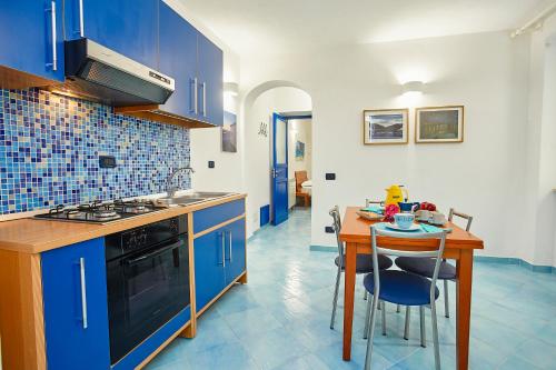 a kitchen with blue cabinets and a wooden table with a dining room at Appartamenti Rosa Dei Venti in Trapani
