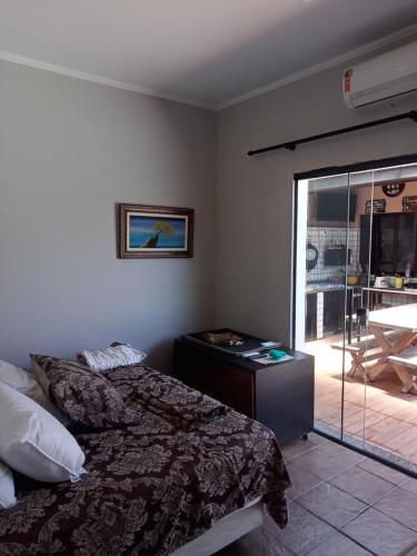 a bedroom with a bed and a sliding glass door at Pousada Muzeli in Itanhaém