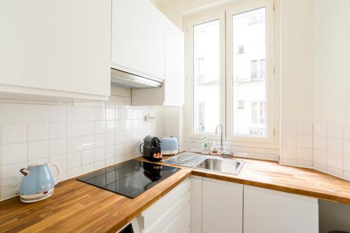 une cuisine blanche avec un évier et une fenêtre dans l'établissement Superbe appartement Montmartre, à Paris