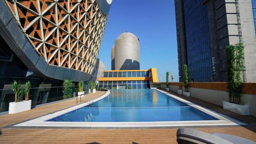 a swimming pool on the roof of a building at Velero Hotel Doha Lusail in Doha