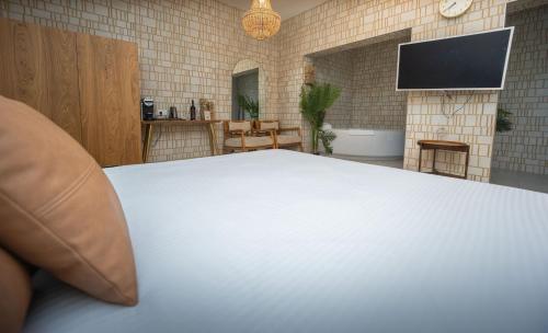 a white bed in a room with a tv at Estate Spa Boutique Hotel - Adults Only in Rechovot