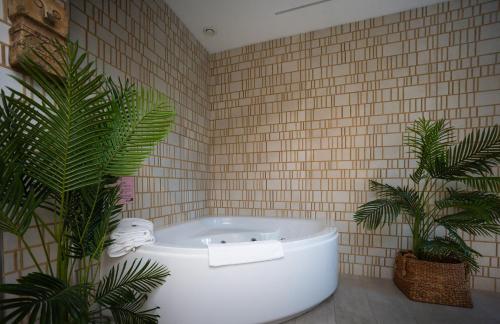 a bathroom with a bath tub and two plants at Estate Spa Boutique Hotel - Adults Only in Rechovot