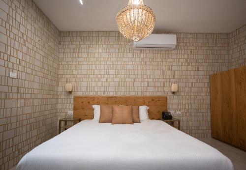 a bedroom with a white bed and a chandelier at Estate Spa Boutique Hotel - Adults Only in Rechovot