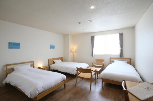 a hotel room with two beds and a desk at Ishigakijima Hotel Cucule in Ishigaki Island
