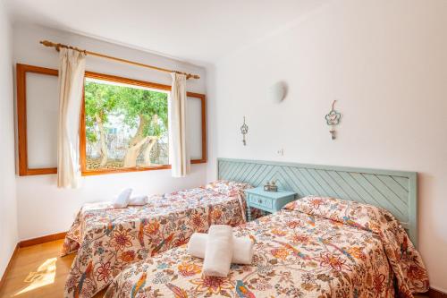 two beds in a room with a window at Gran Sol Family 7 in Felanitx