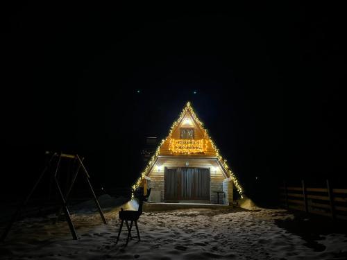 a building with lights on it in the snow at night at Vikendica Monte Pino Romanija in Sokolac