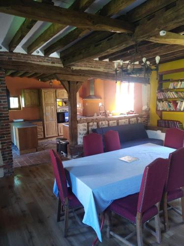 a dining room with a blue table and red chairs at Une maison traditionnelle à la campagne in Fruncé