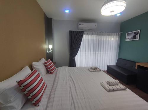 a bedroom with a large white bed with two pillows at อยู่สบายวิลล่า ยโสธร in Yasothon