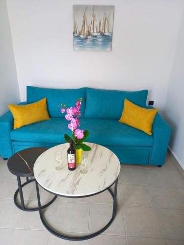 a living room with a blue couch and a table with flowers at KaVros Cozy Apartment in Kavros