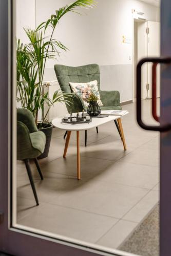 a living room with a green chair and a coffee table at Sonnenschein Hotel & Apartments in Heilbad Heiligenstadt