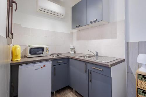 une petite cuisine avec un évier et un micro-ondes dans l'établissement Le Petit Paradis - Studio plage à proximité, à Aregno