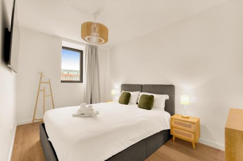 une chambre avec un grand lit blanc et une fenêtre dans l'établissement La Cité des Postiers - Joli duplex climatisé, à Toulouse