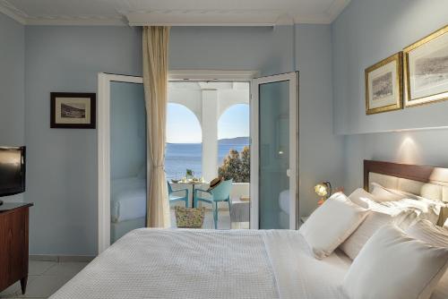a bedroom with a bed and a view of the ocean at Aneroussa Beach Hotel in Batsi
