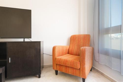 an orange chair sitting in front of a tv at LuxSevilla Moderno Piscina Free Parking in Bormujos