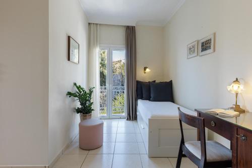 a hotel room with a bed and a desk and a window at Aneroussa Beach Hotel in Batsi