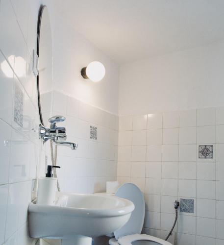 a white bathroom with a sink and a toilet at Dedo Pene Inn in Bansko