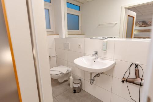 a white bathroom with a toilet and a sink at Sonnenschein Hotel & Apartments in Heilbad Heiligenstadt