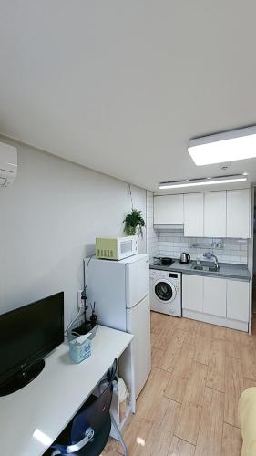 a kitchen with white cabinets and a desk with a tv at Incheon Intl Airport ANN Guest House in Incheon