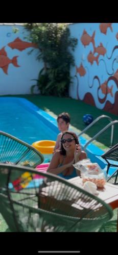 a woman sitting at a table in front of a pool at Sea Wolf Hostel - Lagoa da Conceição in Florianópolis