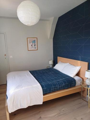 a bedroom with a bed with a blue wall at CHARMANT APPARTEMENT à 150 M des THERMES et du CENTRE VILLE in Thonon-les-Bains