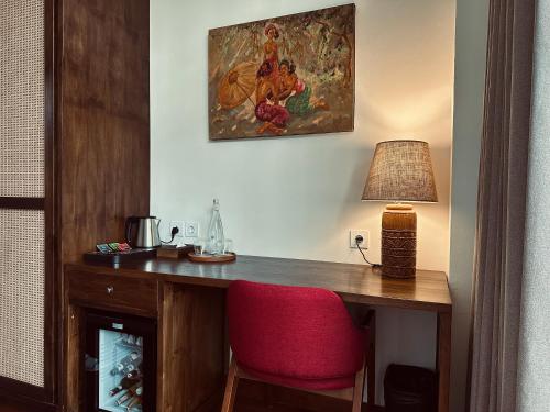 a room with a desk with a lamp and a red chair at Plawa Laguna Bali in Canggu