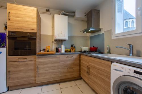 une cuisine avec des armoires en bois et une laveuse et une sécheuse dans l'établissement L'Harmonie de Bourges - Charmant appt plein centre, à Bourges