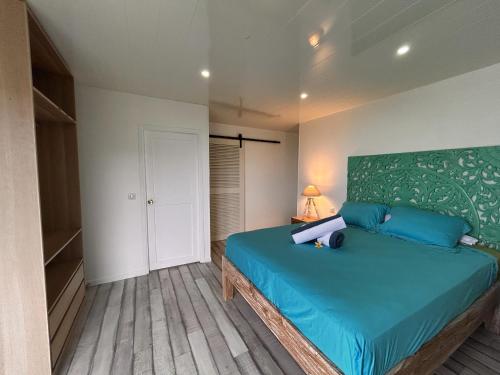 a bedroom with a bed with a green headboard at Moorea - Villa Pool & Chill in Maharepa