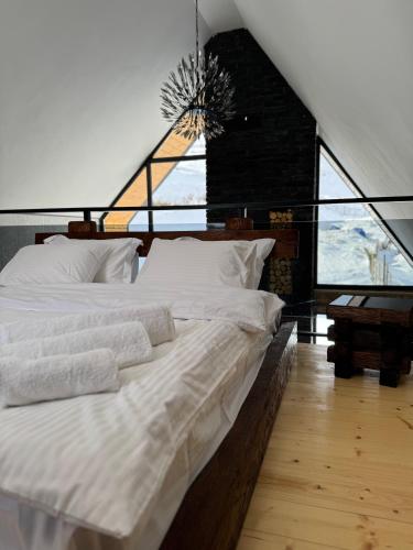 a bedroom with a large white bed with a large window at Cottage River Sound in Kazbegi