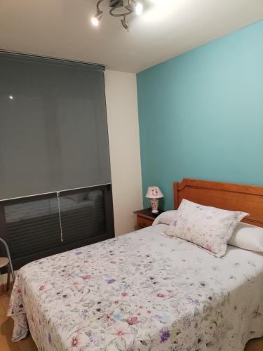 a bedroom with a bed with a floral bedspread at Apartamentos Chevere Azul con Garaje in Oviedo