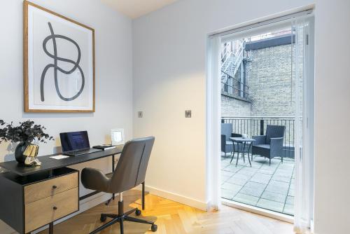 an office with a desk with a computer and a balcony at Urban Chic - Camden in London