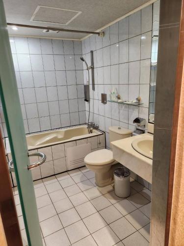 a bathroom with a toilet and a tub and a sink at 爵起商務飯店 in Taoyuan
