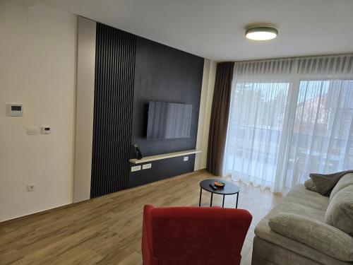 a living room with a couch and a red chair at Apartman FIŠBAH II 2 self CHECK-IN, FREE PRIVATE PARKING in Osijek