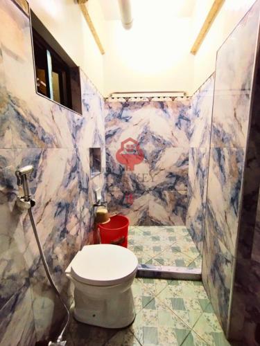 ein Badezimmer mit Toilette und Marmorwand in der Unterkunft The Key Transient in La Trinidad