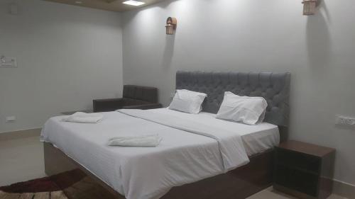 a bedroom with a large bed with white sheets and pillows at Hotel Hangout in Jangipur