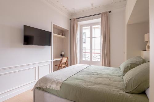 une chambre avec un lit et une télévision sur un mur dans l'établissement Amazing flat - center of paris, à Paris