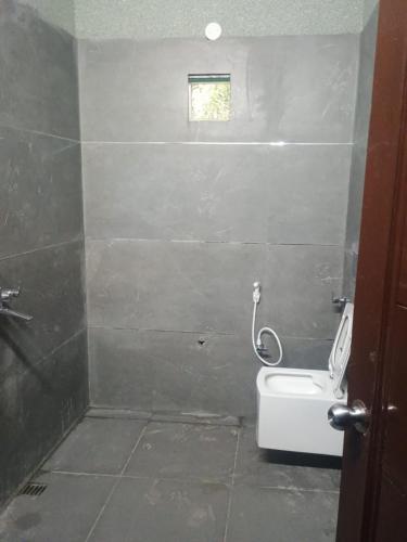 a bathroom with a toilet and a small window at Kingsman in Katra